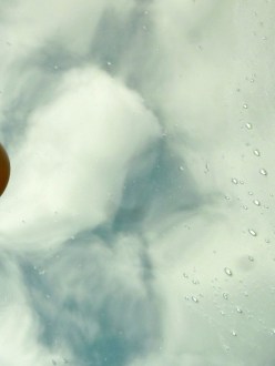 Red ball on reflective water, cloud reflections