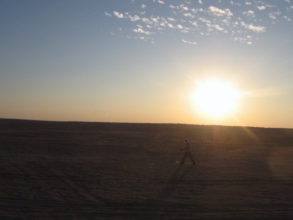Bedouin walks past sunset in Sahara desert